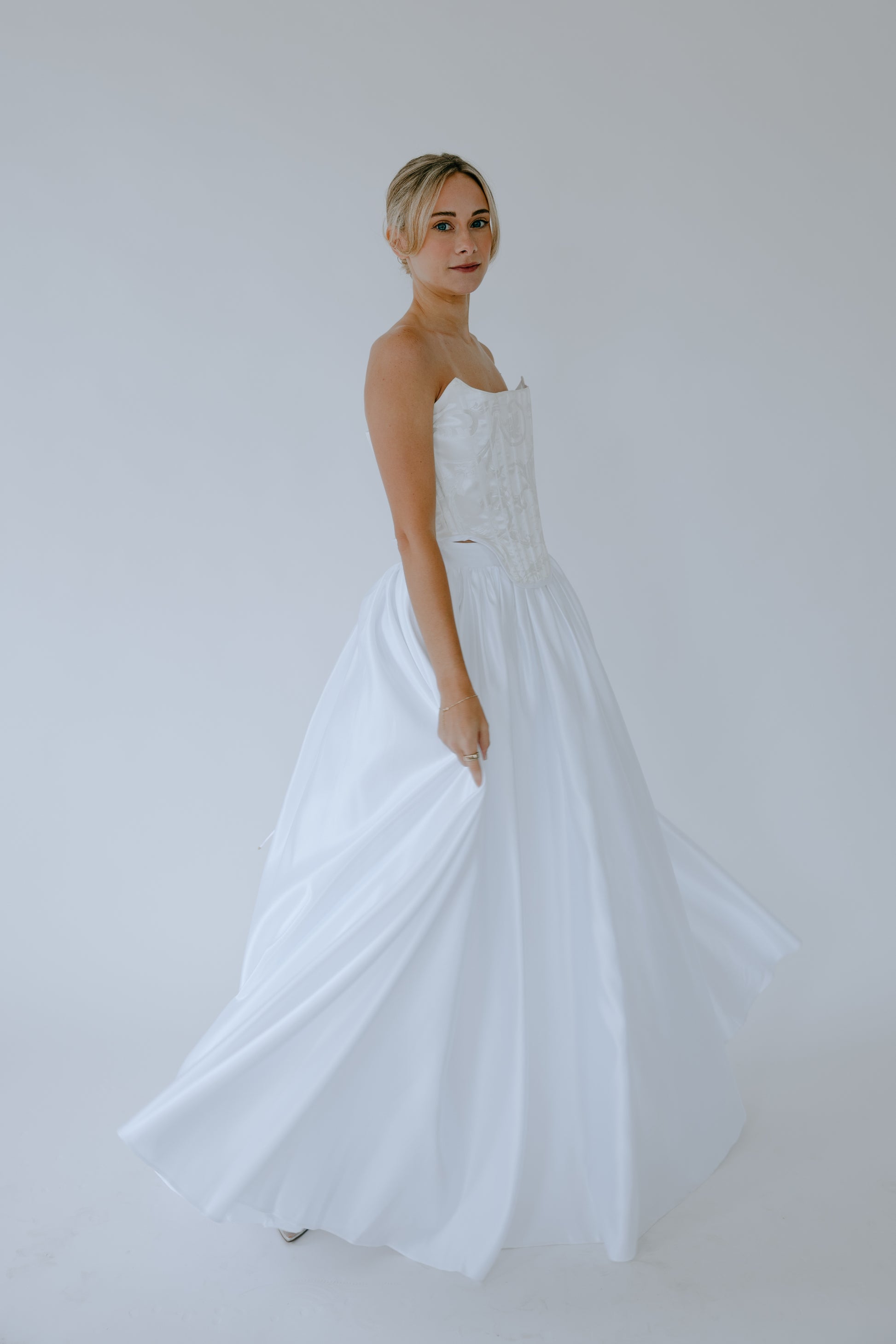 Woman wearing a bridal corset dress against a plain background