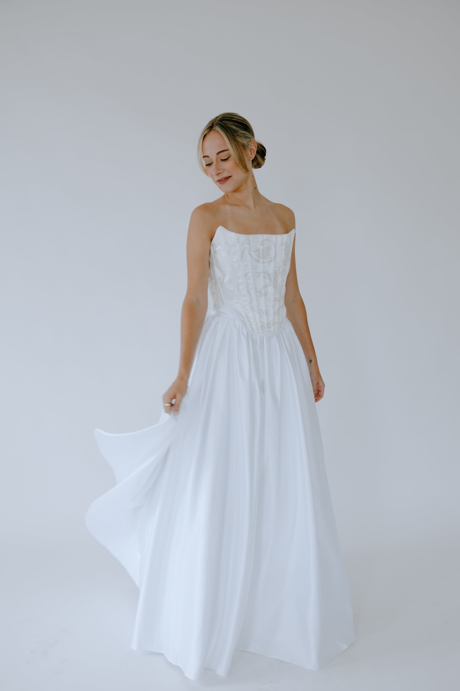 Woman wearing a white bridal wedding dress against a plain background