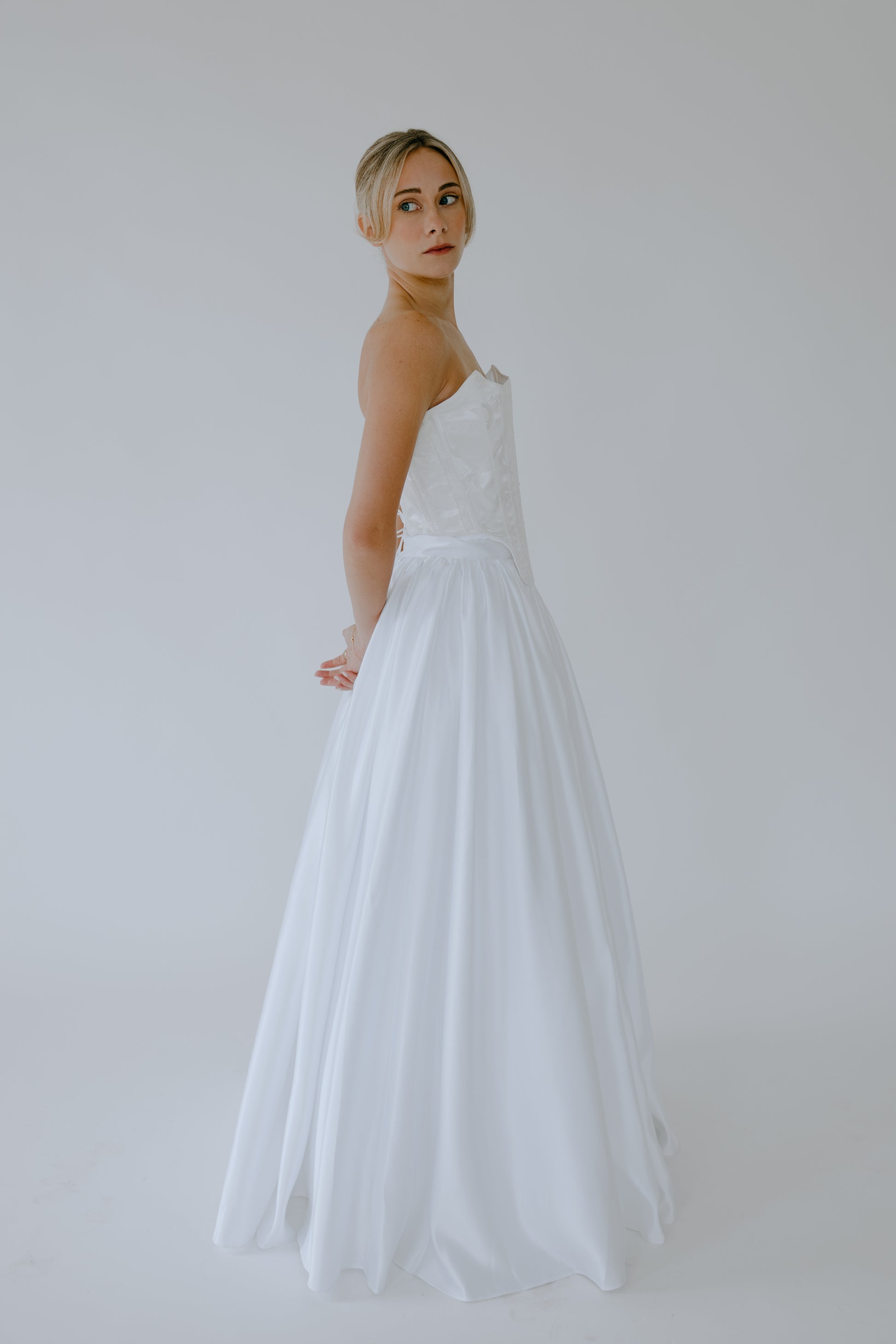 Woman wearing a wedding dress against a plain background