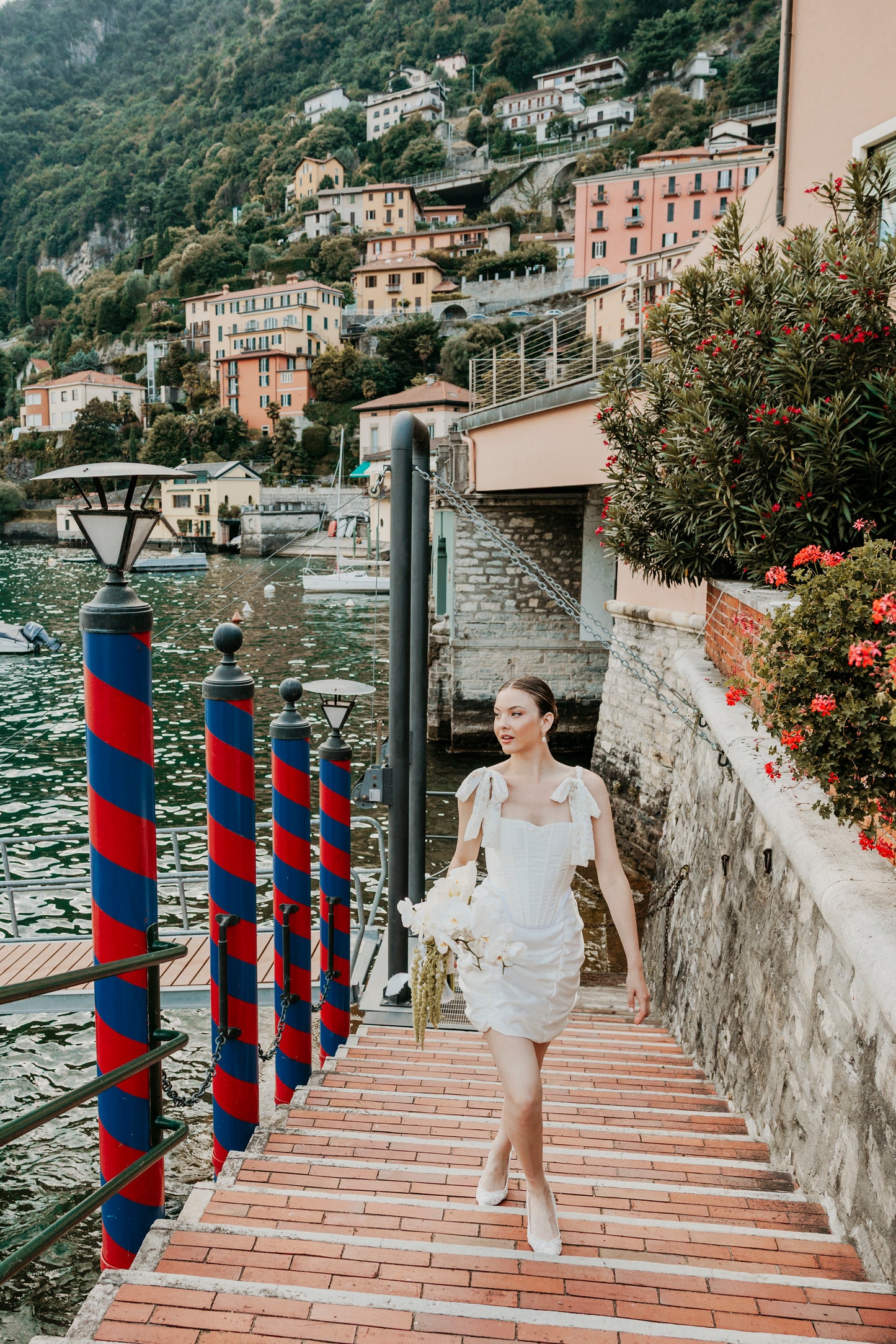 Woman in a corset in lake como with buildings and mountains in the background.