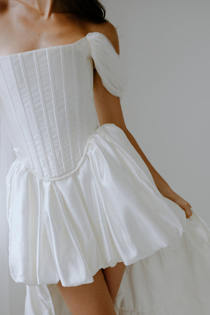 White off-shoulder wedding dress with a plain background